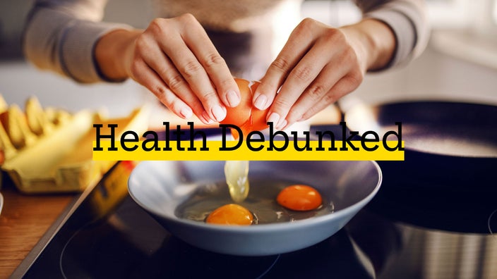 Close-up of a woman breaking an egg into a frying pan.