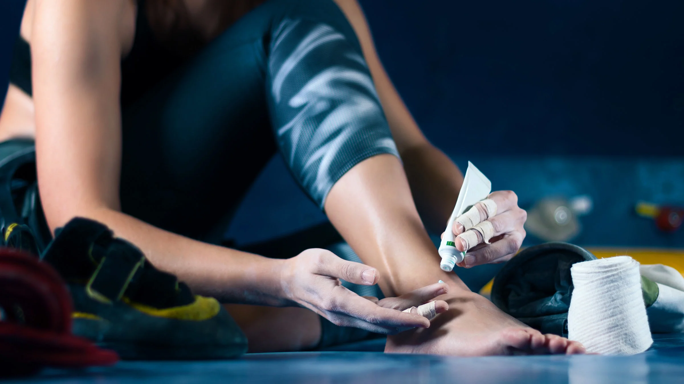 An athlete applying wound cream to their ankle.