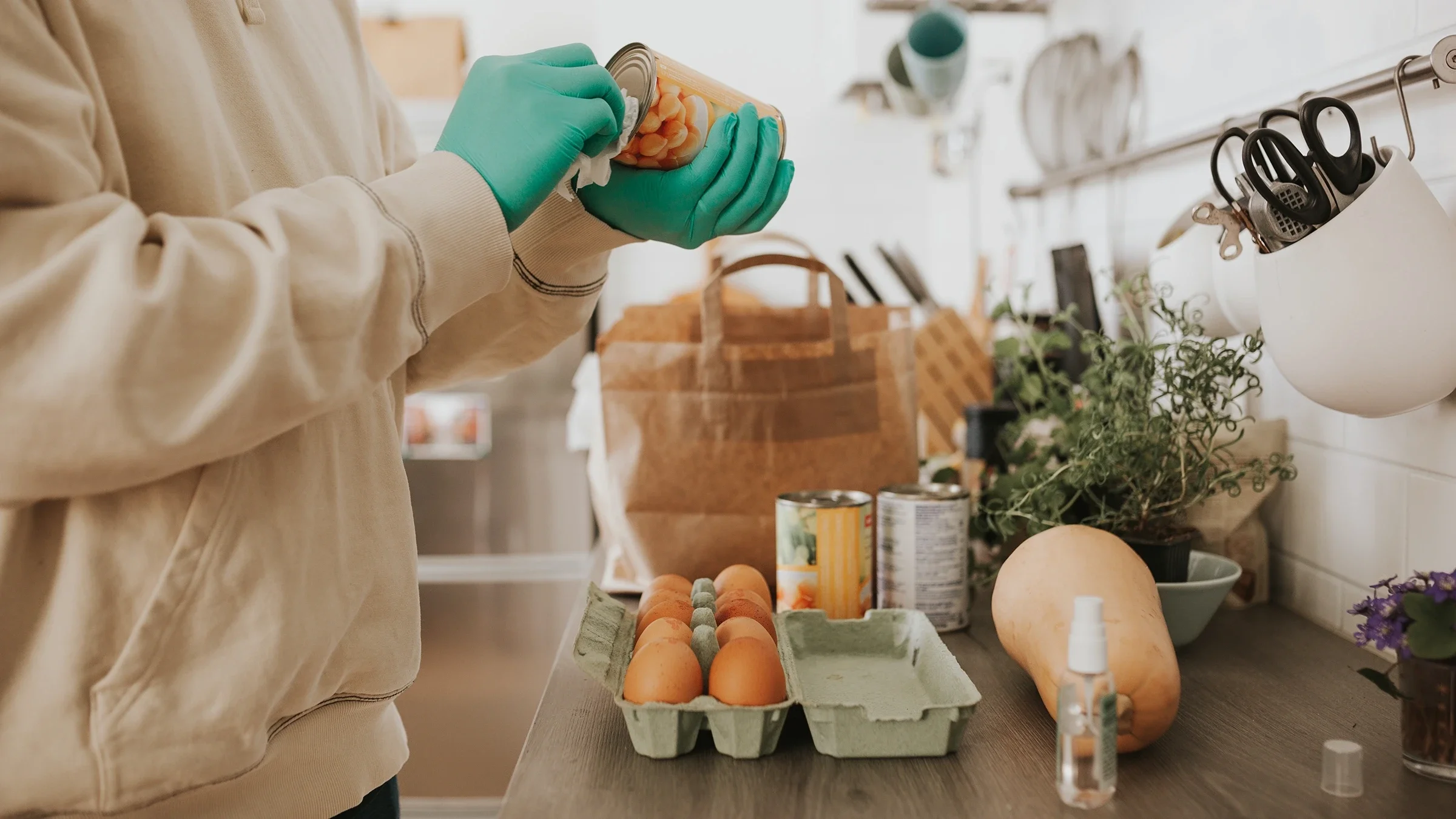 Cropped shot of a man wiping down groceries in his kitchen during the pandemic.