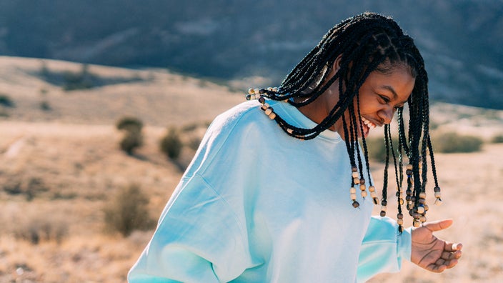 A young girl laughs while walking through the desert. 
