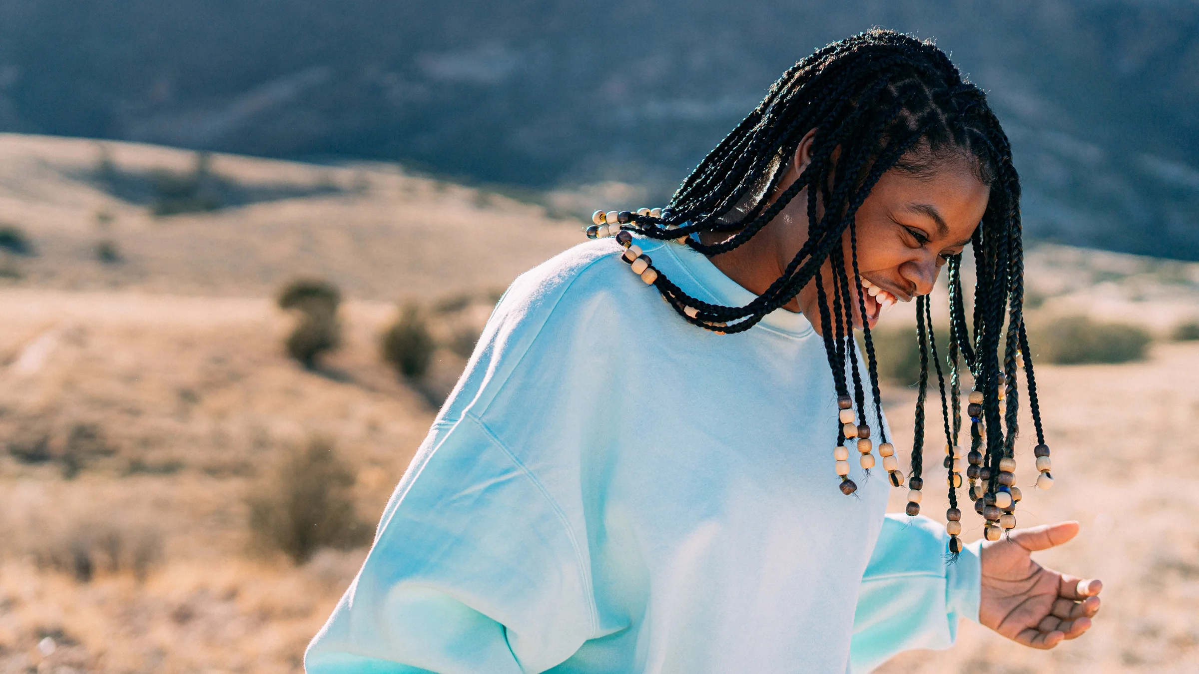 A young girl laughs while walking through the desert.