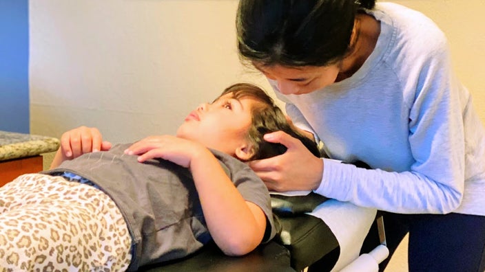 Alyssa Lauren Stone’s daughter is pictured lying on a table in a medical office getting a chiropractic treatment.