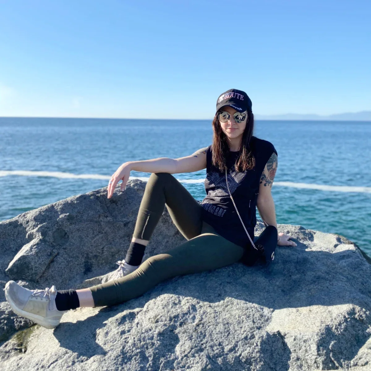 Michelle Andrade is pictured sitting on a rock by the sea.