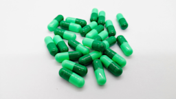 Pile of green capsule pills on a gray background.
iStock via Getty Images