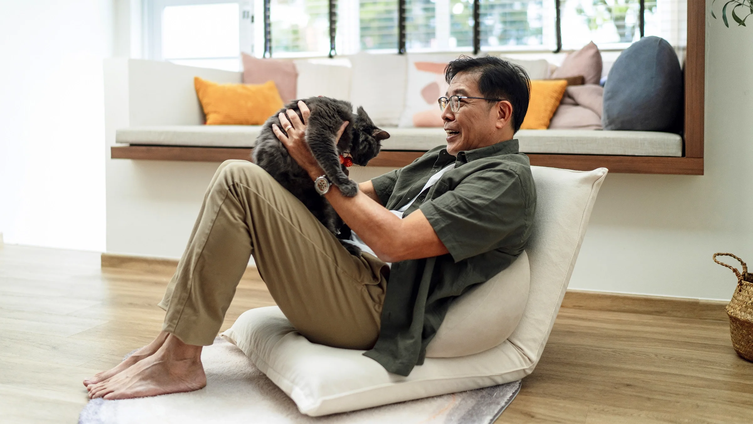 A man is enjoying time with his cat at home.