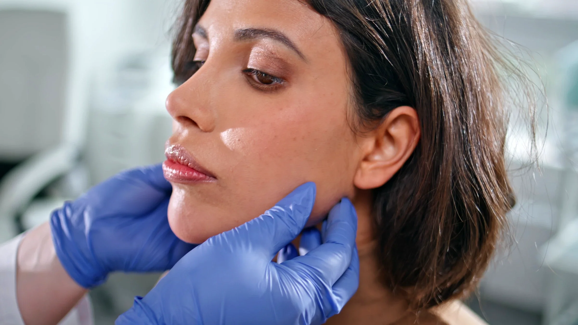 Healthcare professional examining woman’s face.