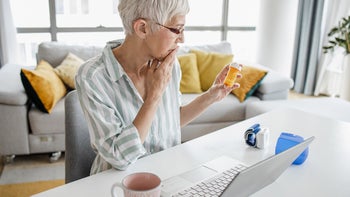 Health: Evista: senior woman thinking and reviewing medication bottle-1338752579