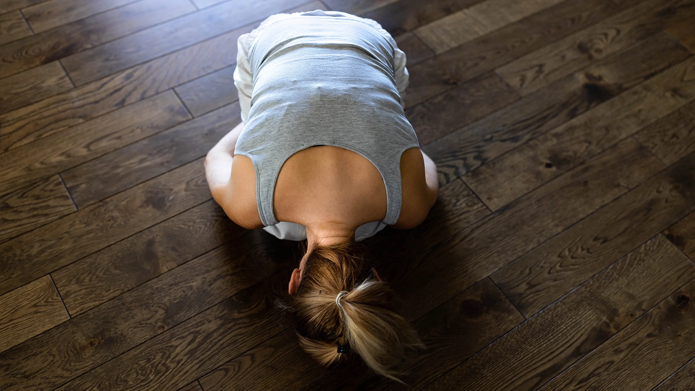 High angle view of woman bending forward with head on the floor