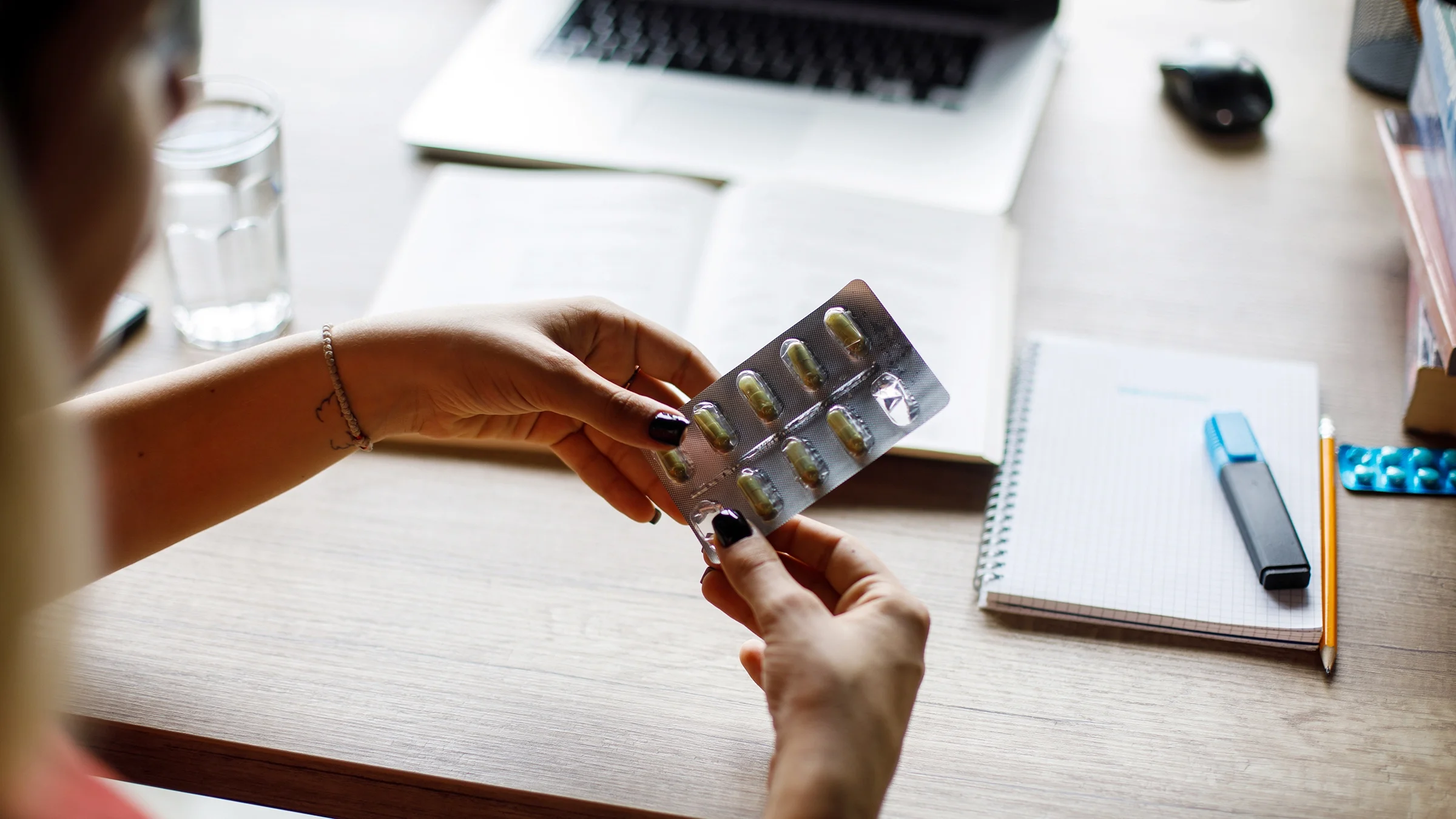 A person retrieves a medicine capsule out of a blister package.