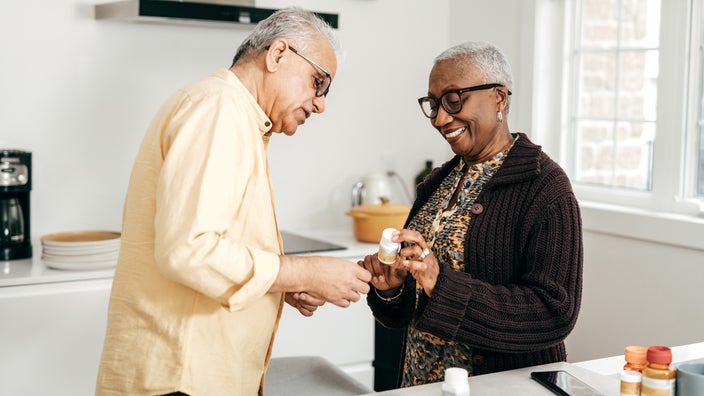 Elderly couple reviewing their prescriptions together in the kitchen.