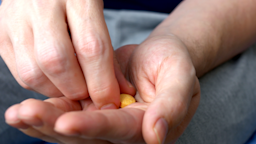 A man prepares to take a yellow pill that’s sitting in the palm of his hand.
Ivan Zhaborovskiy/iStock via Getty Images Plus