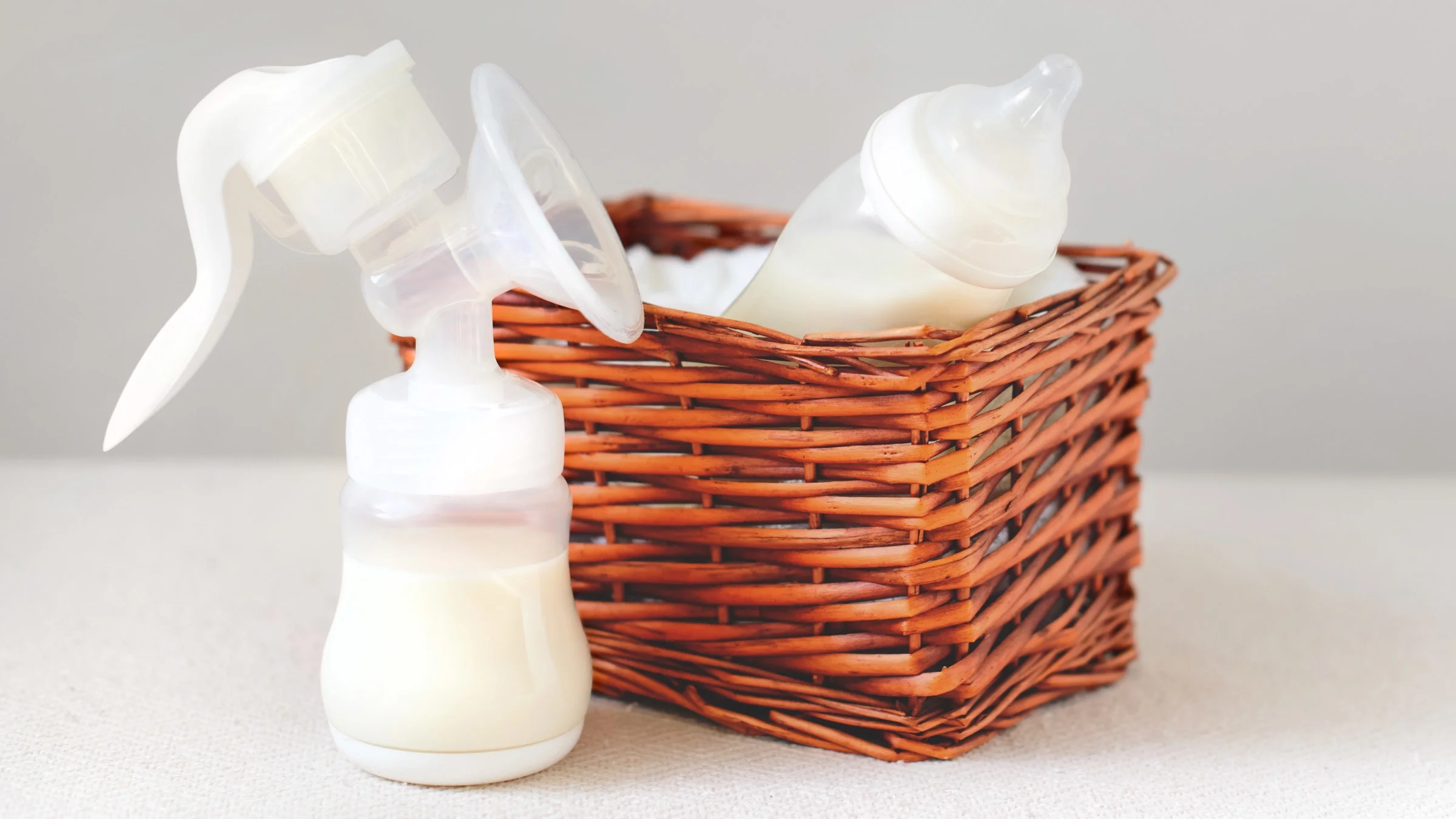 A breast pump, next to a basket containing a baby bottle. 