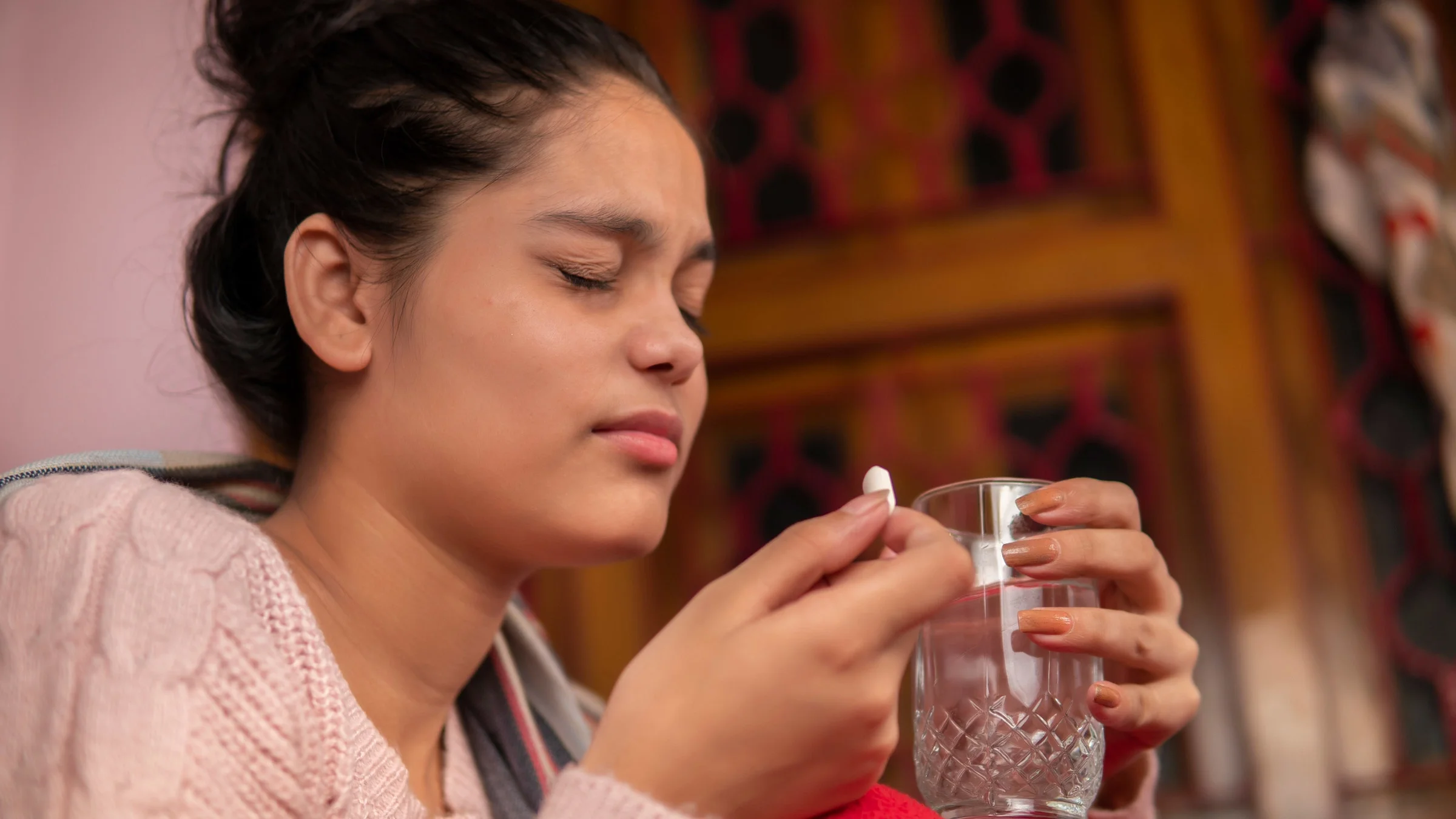 An anxious person closing their eyes and taking a pill. 