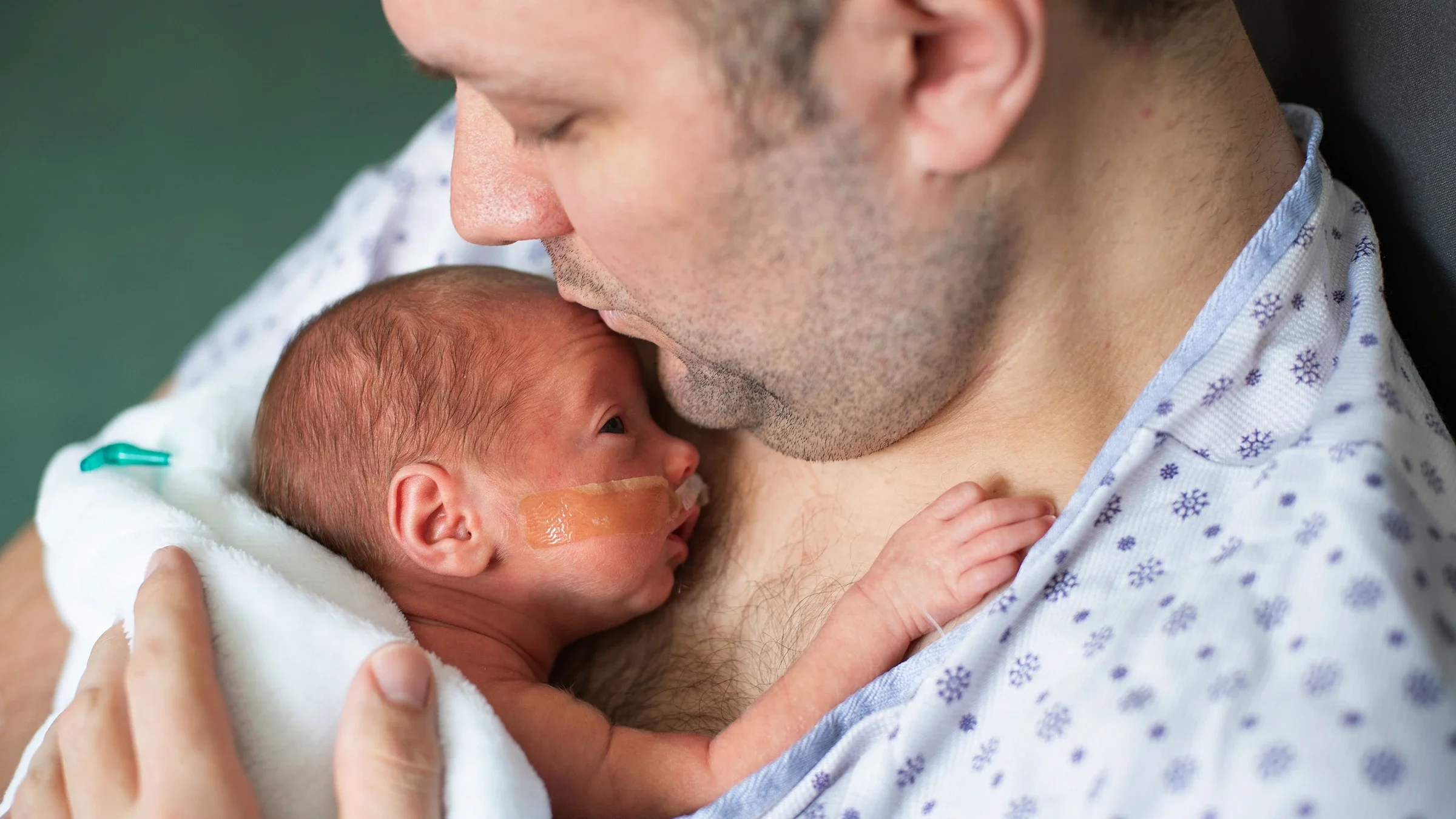 A father cuddles his premature baby via skin-to-skin contact at the hospital.