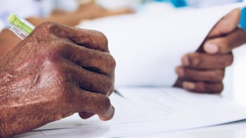 elderly hands writing paperwork-1134909178