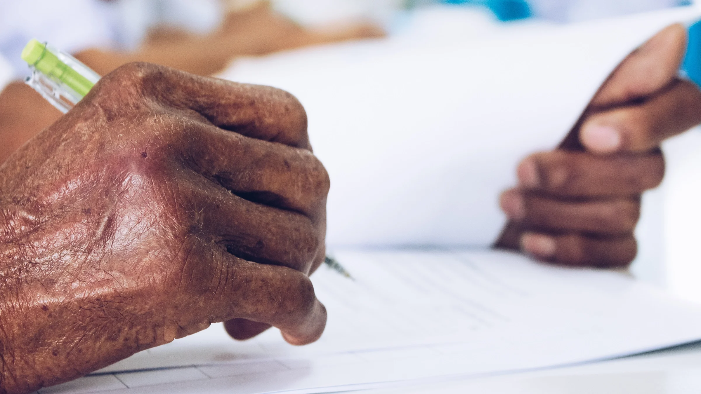 Extreme close-up of an elderly person's hands writing with a pen.