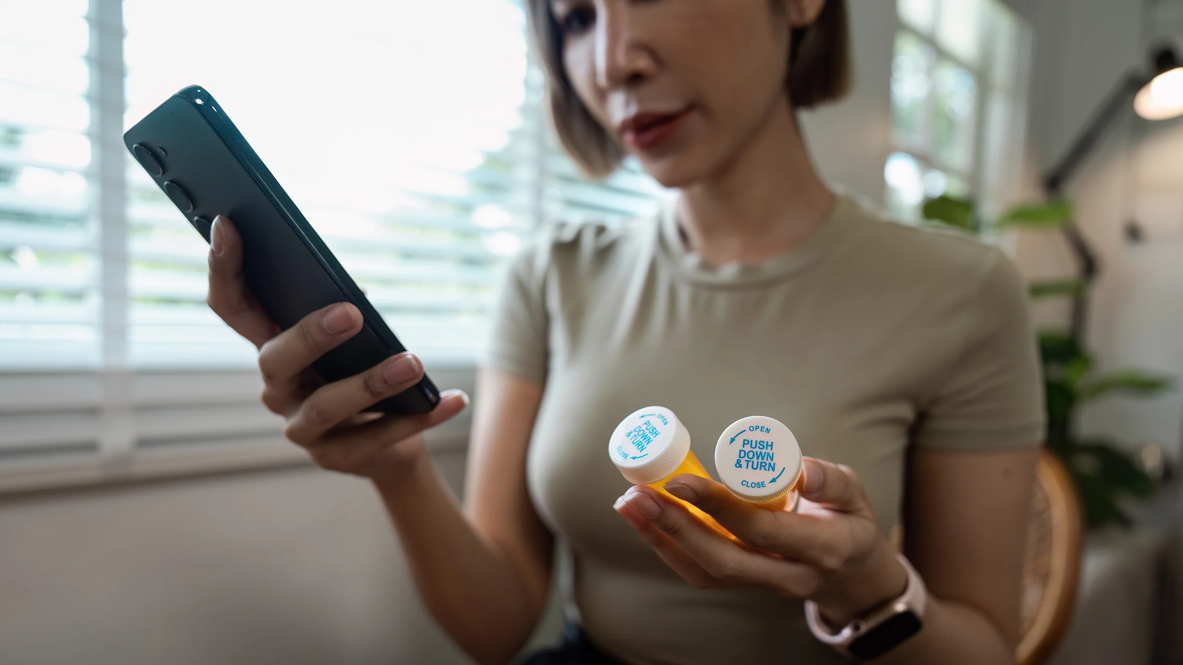 A woman is using her smartphone to check information on a medication.