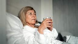 A woman is holding a glass of water in bed.
ti-ja/iStock via Getty Images Plus