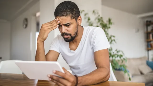 mental health: anxiety: man looking concerned at tablet 1052570996