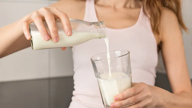 acne: diet nutrition: dairy: woman pouring milk into glass 519686480