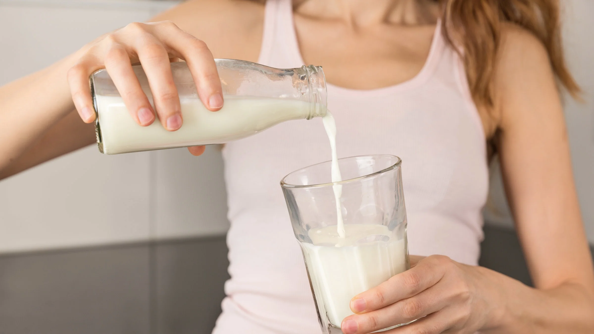 Close-up of a woman pouring milk into a glass.