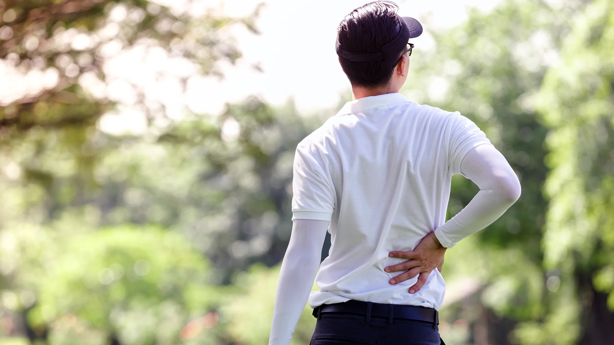 A golfer touches his lower back as he experiences side pain.