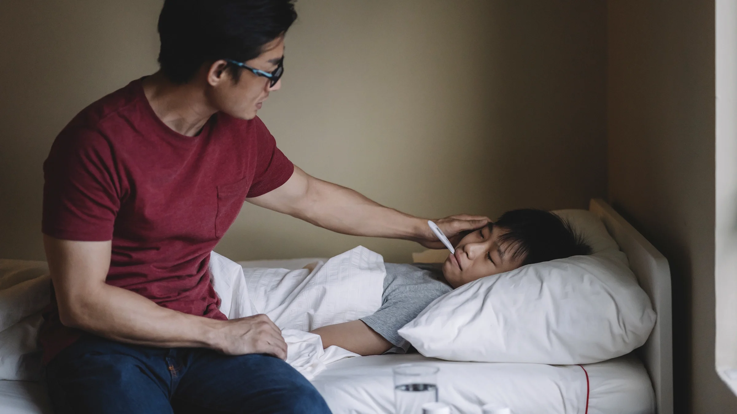 A man checking a boy’s temperature with a thermometer