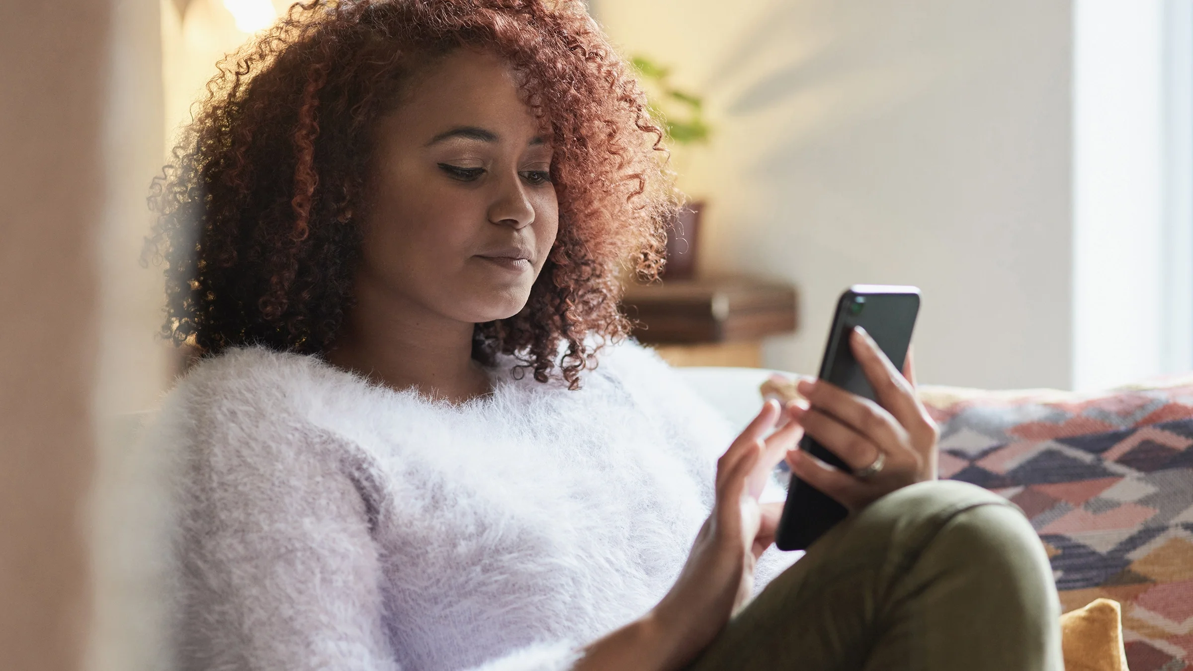 A young woman is on her cell phone at home.