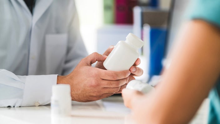  A close-up image depicts a pharmacist consulting with a patient about medication.