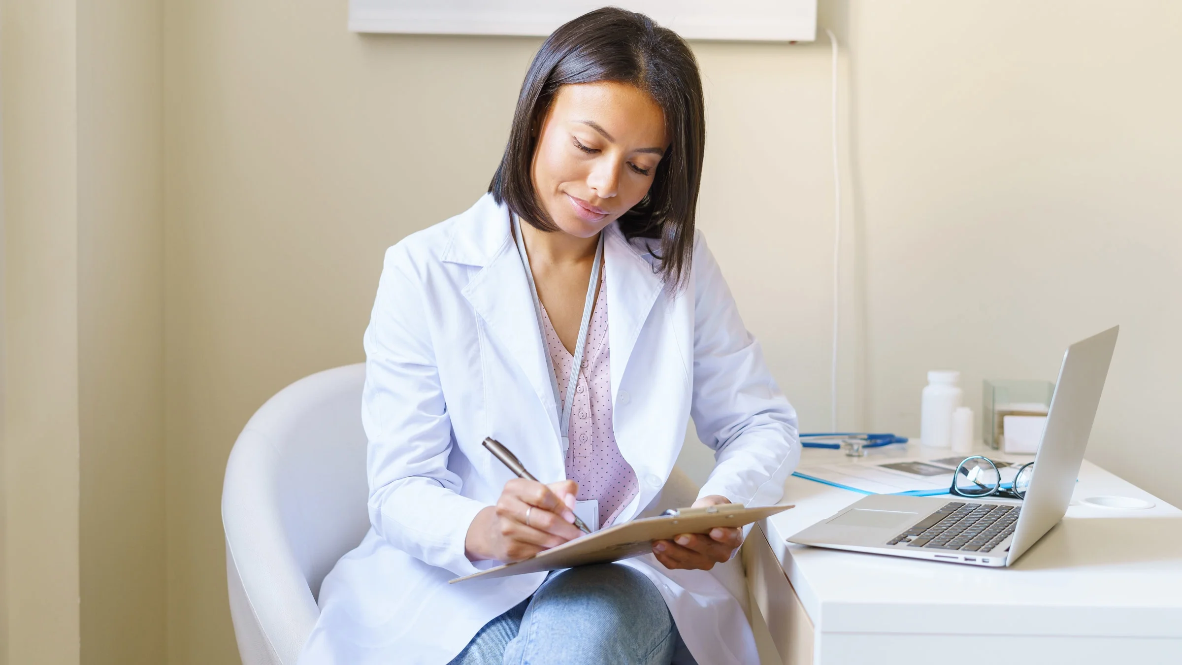A doctor sitting at a desk and filling out forms.