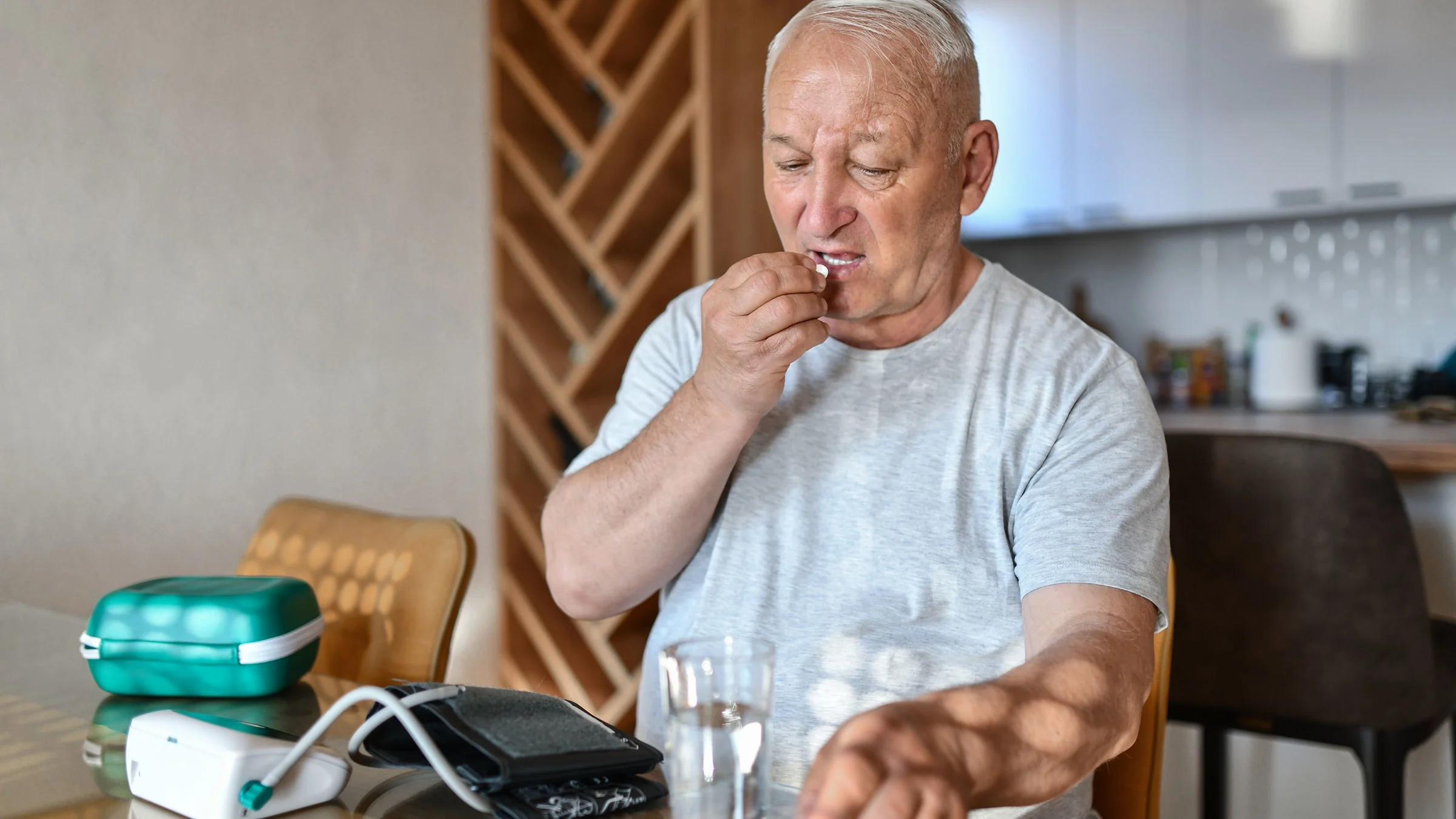 A man takes his medication after measuring his blood pressure.