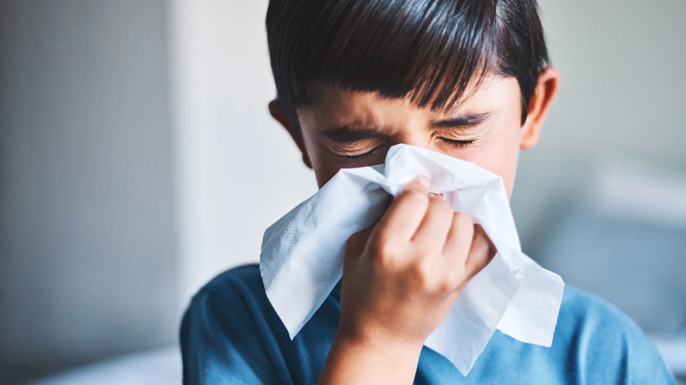 Child blowing nose with tissue.