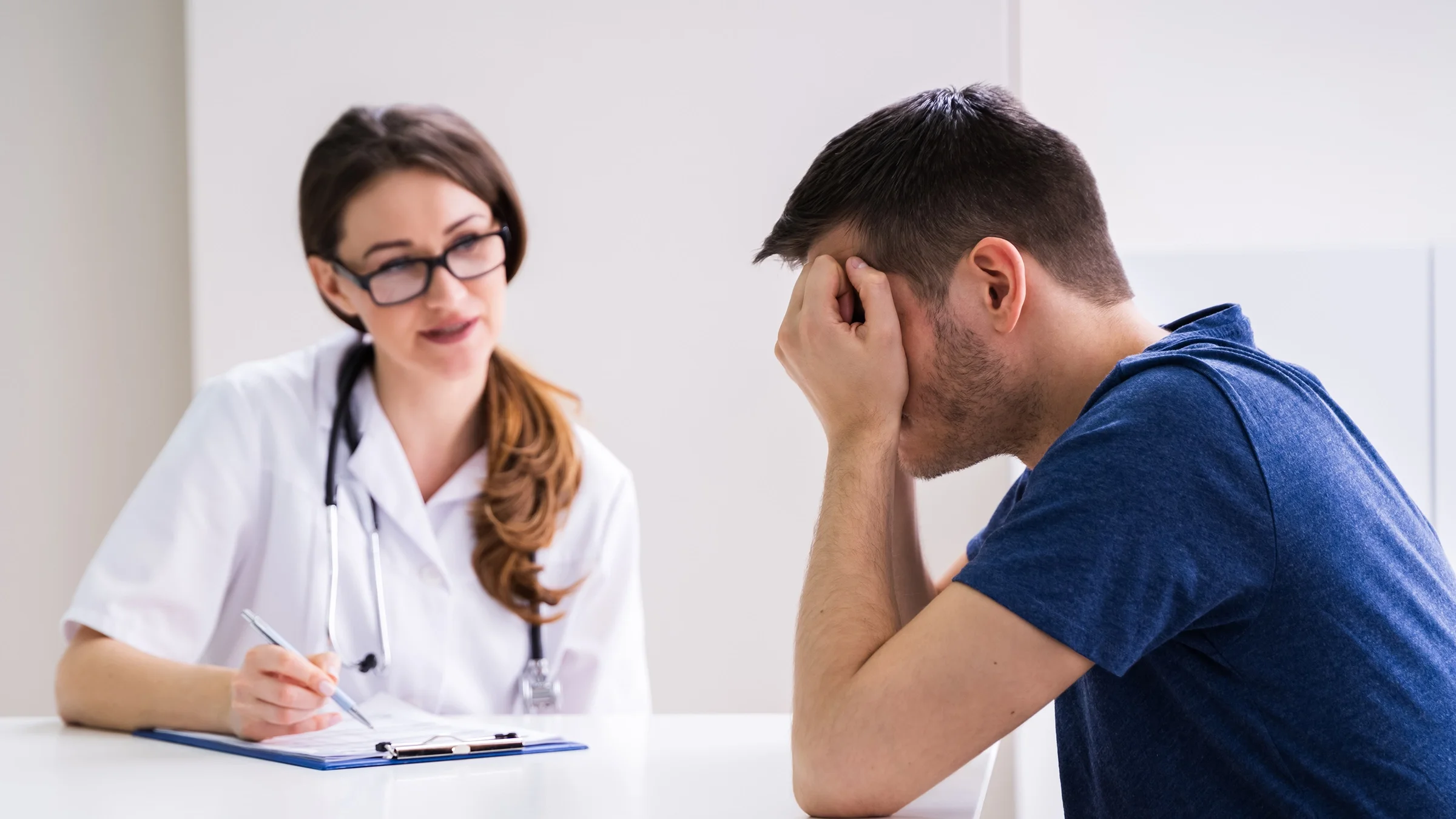 Doctor consoling a man who looks sad and stressed with his head held in his hands.