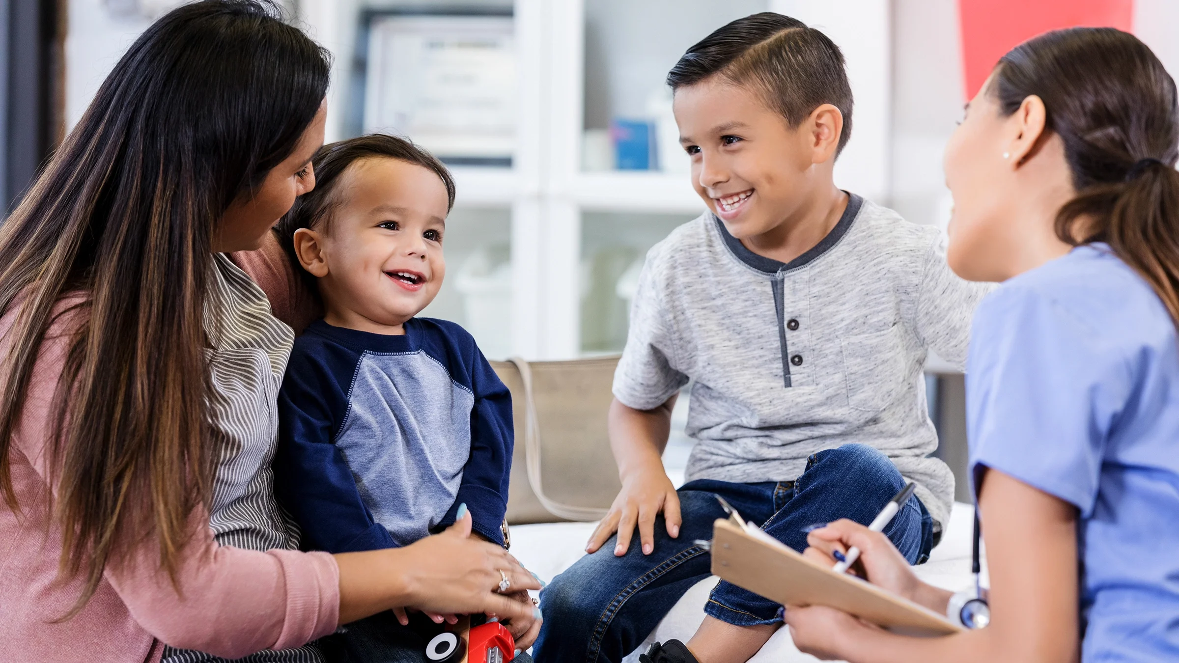 A mother and two sons sit with a medical professional.