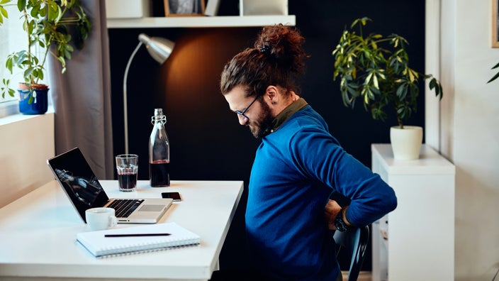 Man sitting in his home office with back pain.