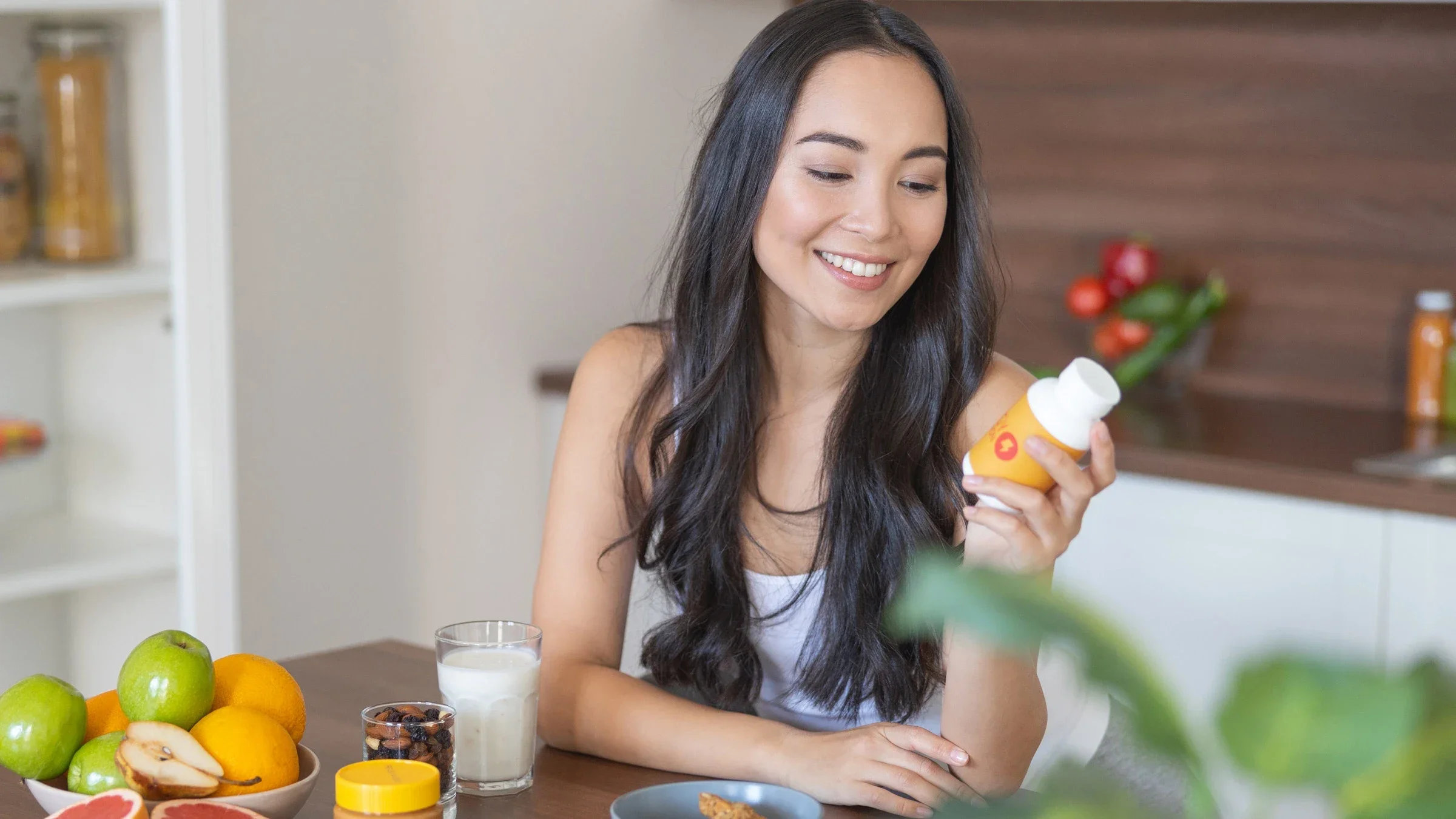 A person looking at a supplement bottle while eating breakfast.
yacobchuk/iStock via Getty Images Plus