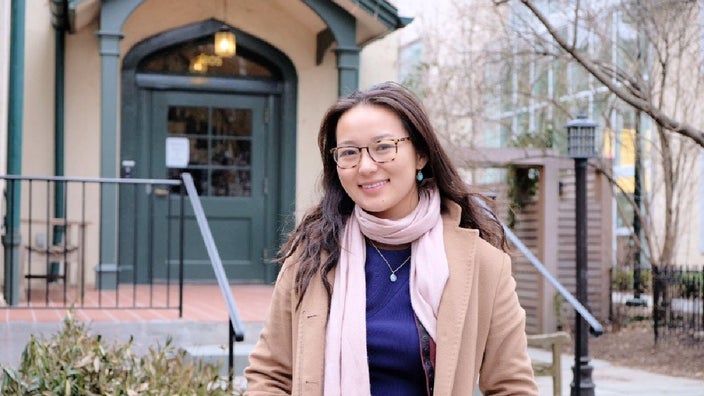 Sabrina Qiao is pictured outside, wearing a scarf and coat.