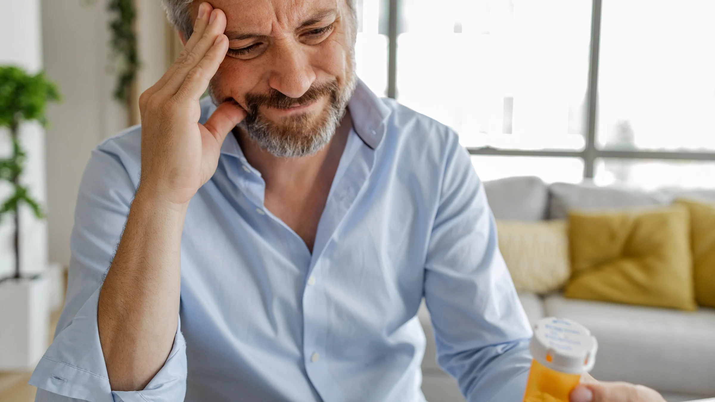 Cropped shot of a man looking confused at his prescription bottle in his hand.