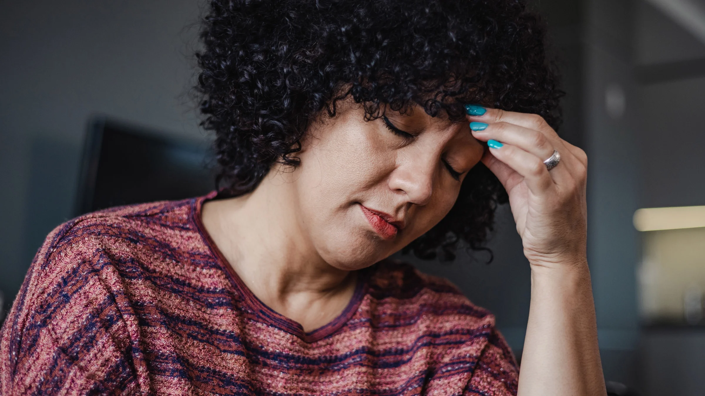 A woman clutches her forehead as she suffers from a migraine.