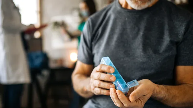Side effects: closeup man with pill organizer 1293211998