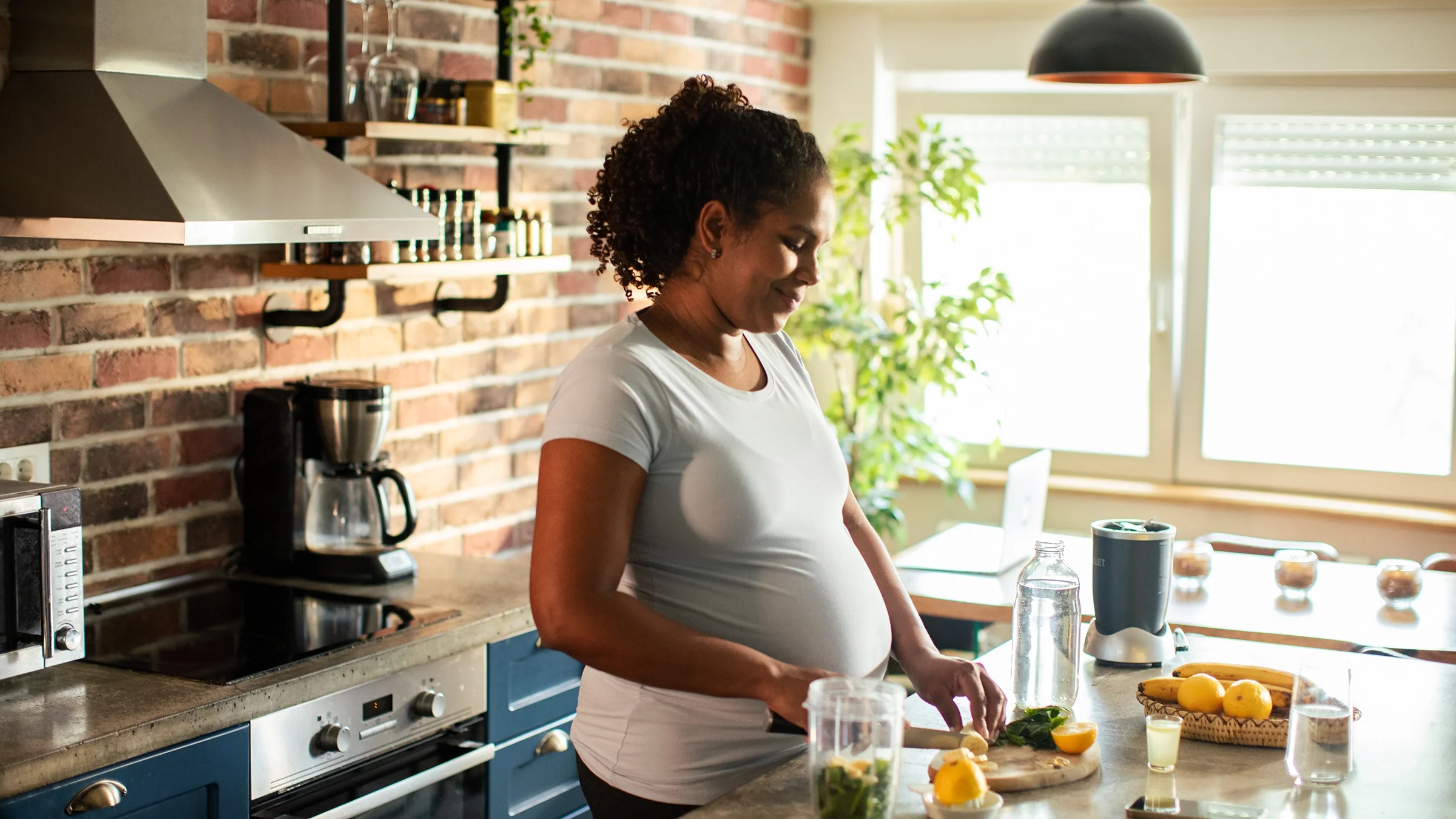 Pregnant woman preparing a meal in the kitchen.
