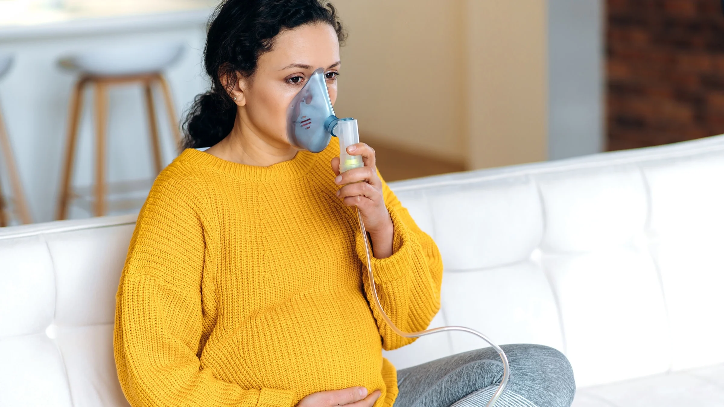 Portrait of a pregnant woman using an over the nose inhaler.