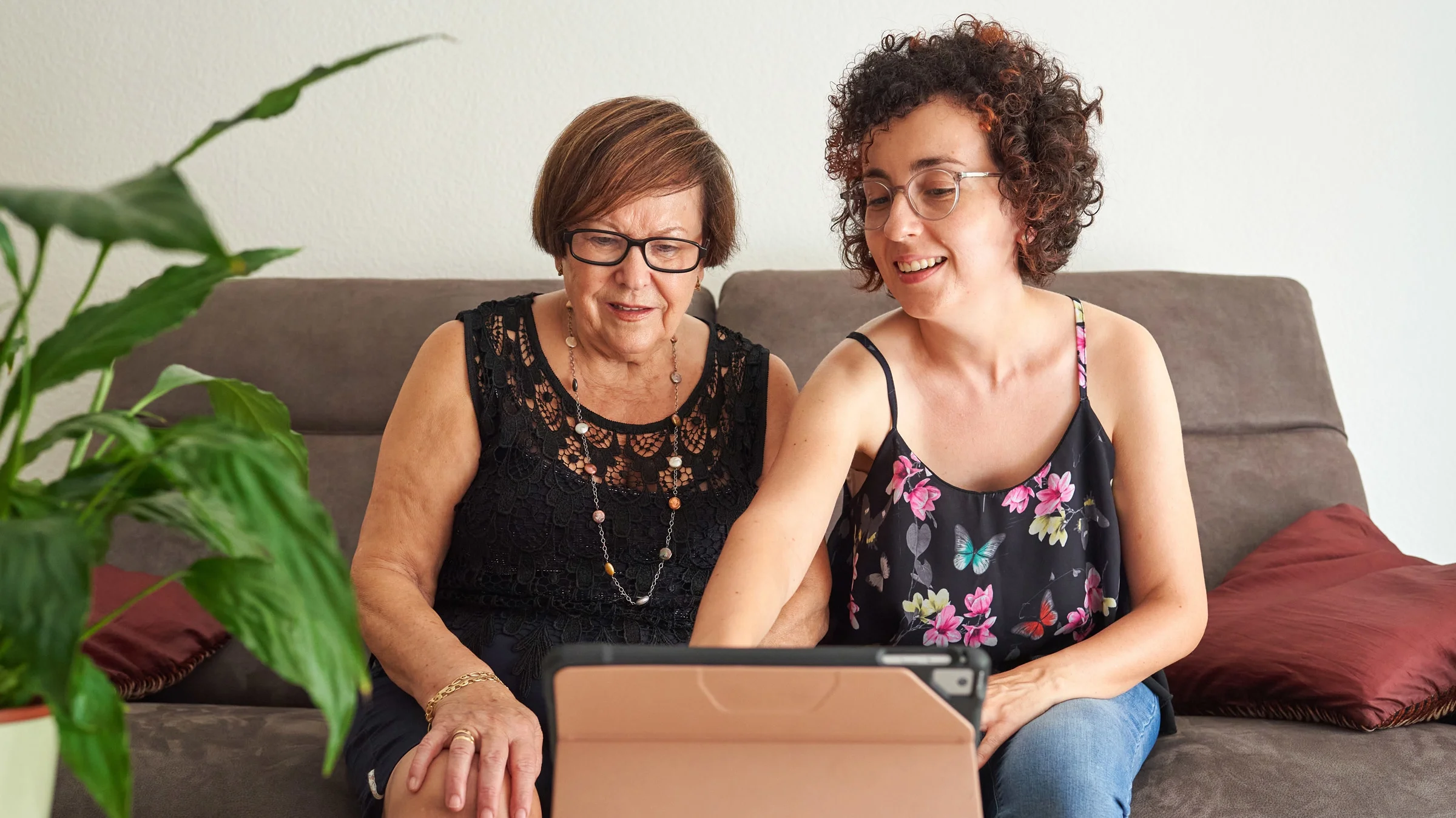 A young adult helping their grandparent use a tablet.