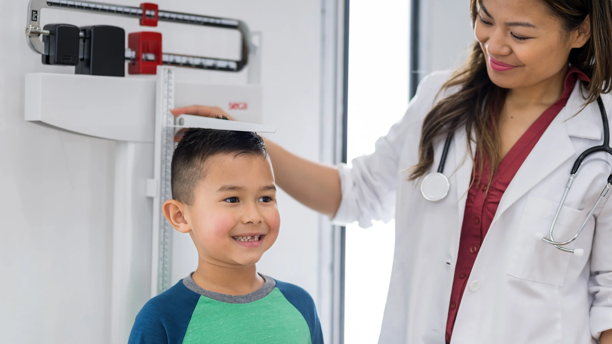 Healthcare professional measures a child's height at an appointment.