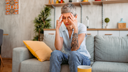 A woman sits on a living room sofa, feeling lightheaded.
urbazon/E+ via Getty Images