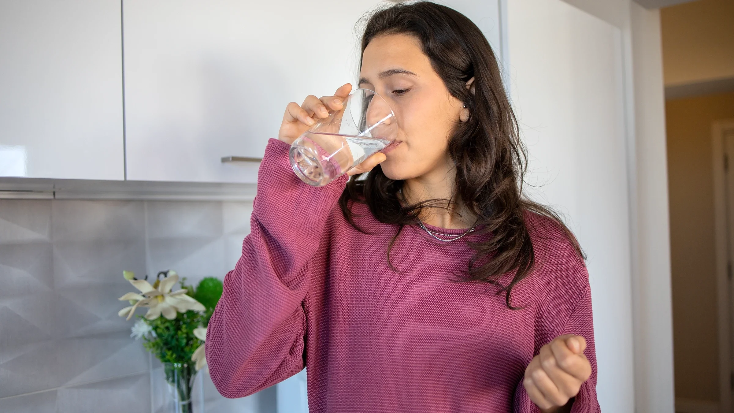 A woman is taking medication with a glass of water.