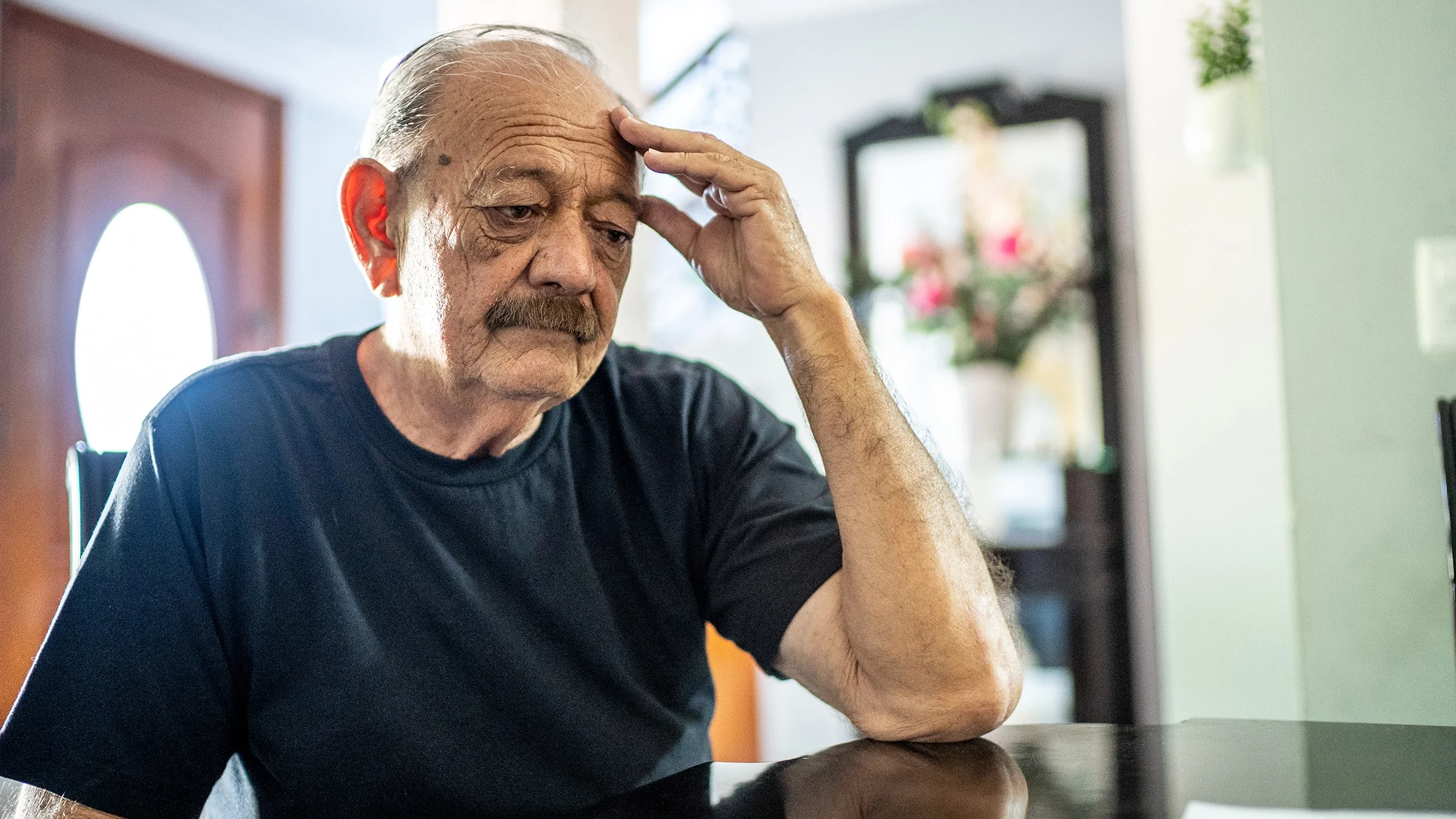 Older man being worried with hand on head at home.