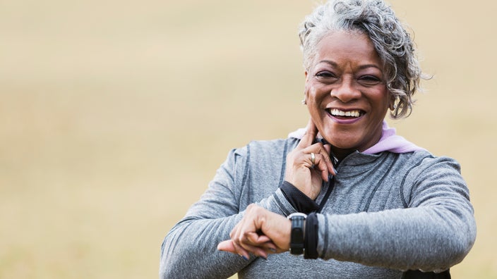 Portrait of a senior woman smiling and taking her pulse after she has worked out.