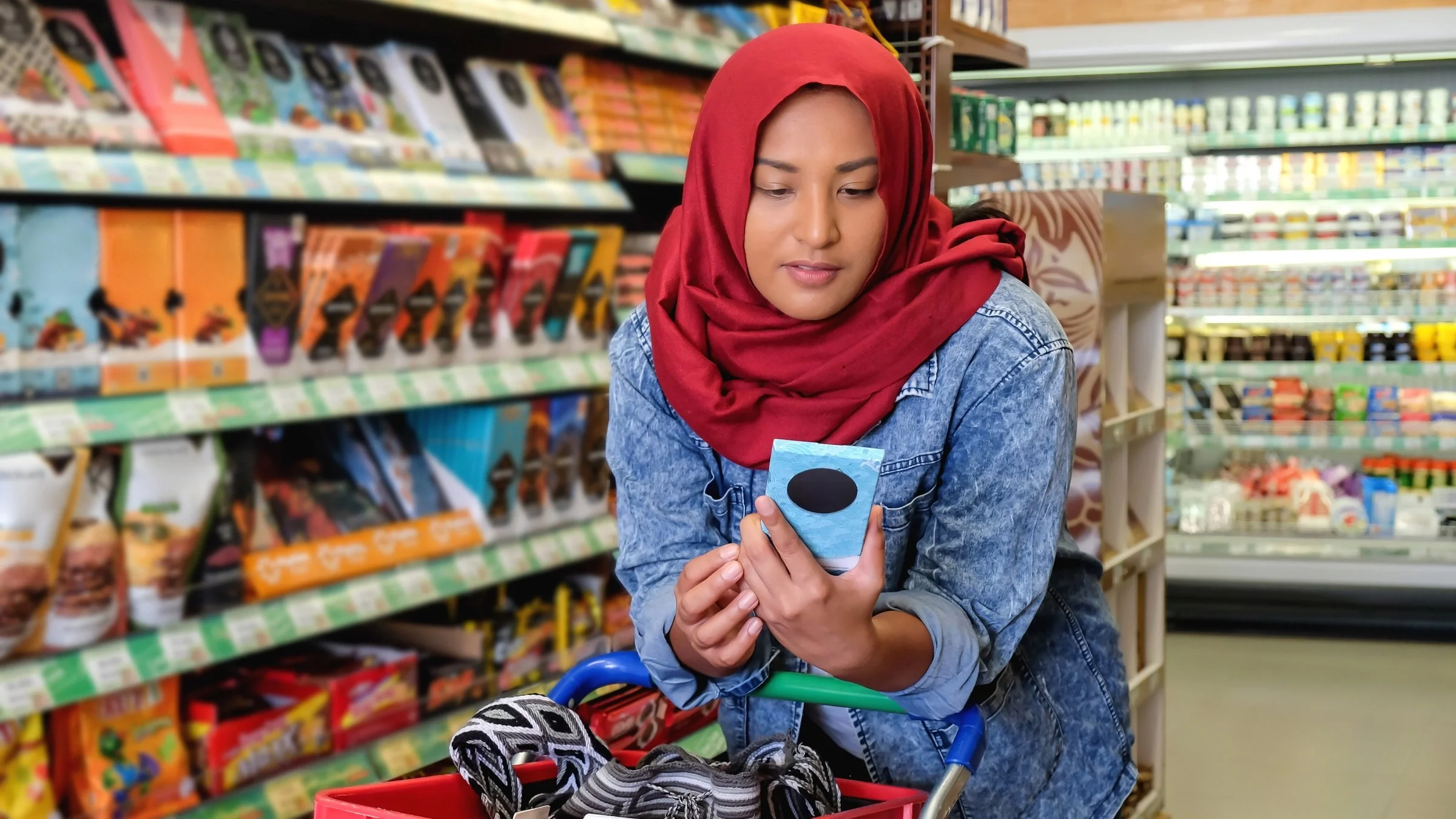 A customer reading a chocolate bar label in a grocery aisle.