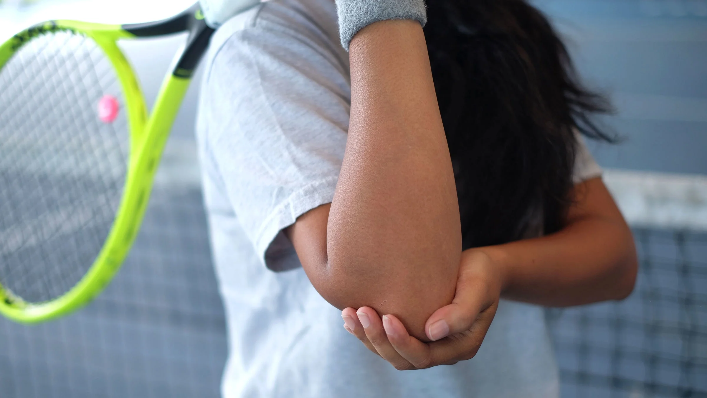 A woman with tennis elbow is holding her arm. 